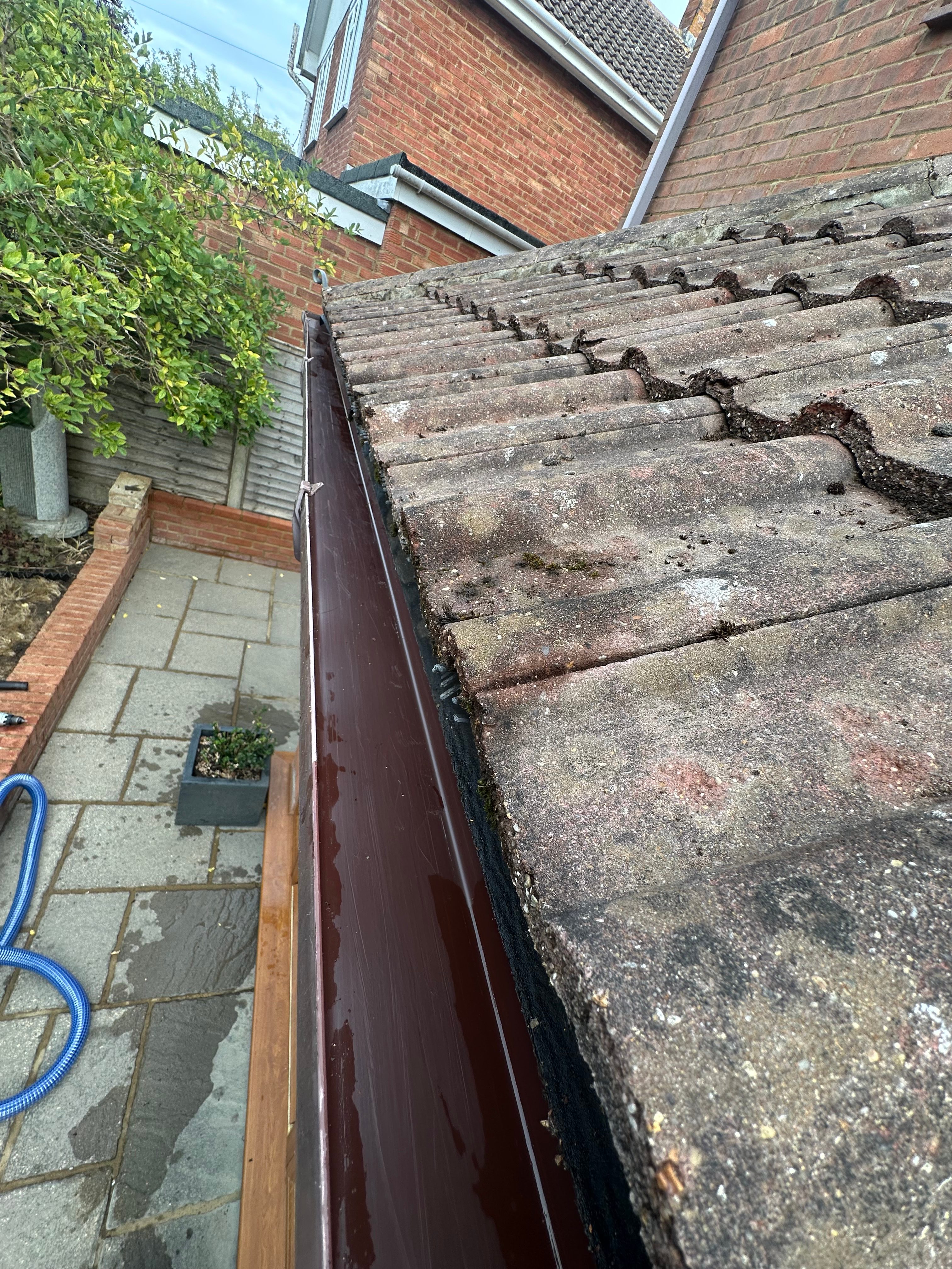 Professional operative cleaning moss from a UK residential tiled roof in Aylesbury